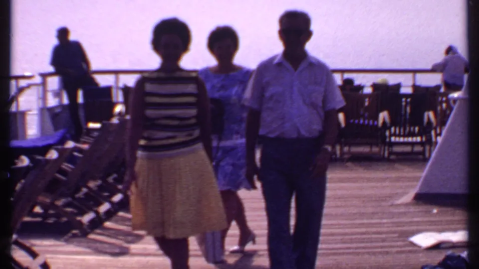 The three adults move nearer the camera on the 1969 Bahamas cruise deck, framed by rows of lounge chairs and bright water beyond the rail.