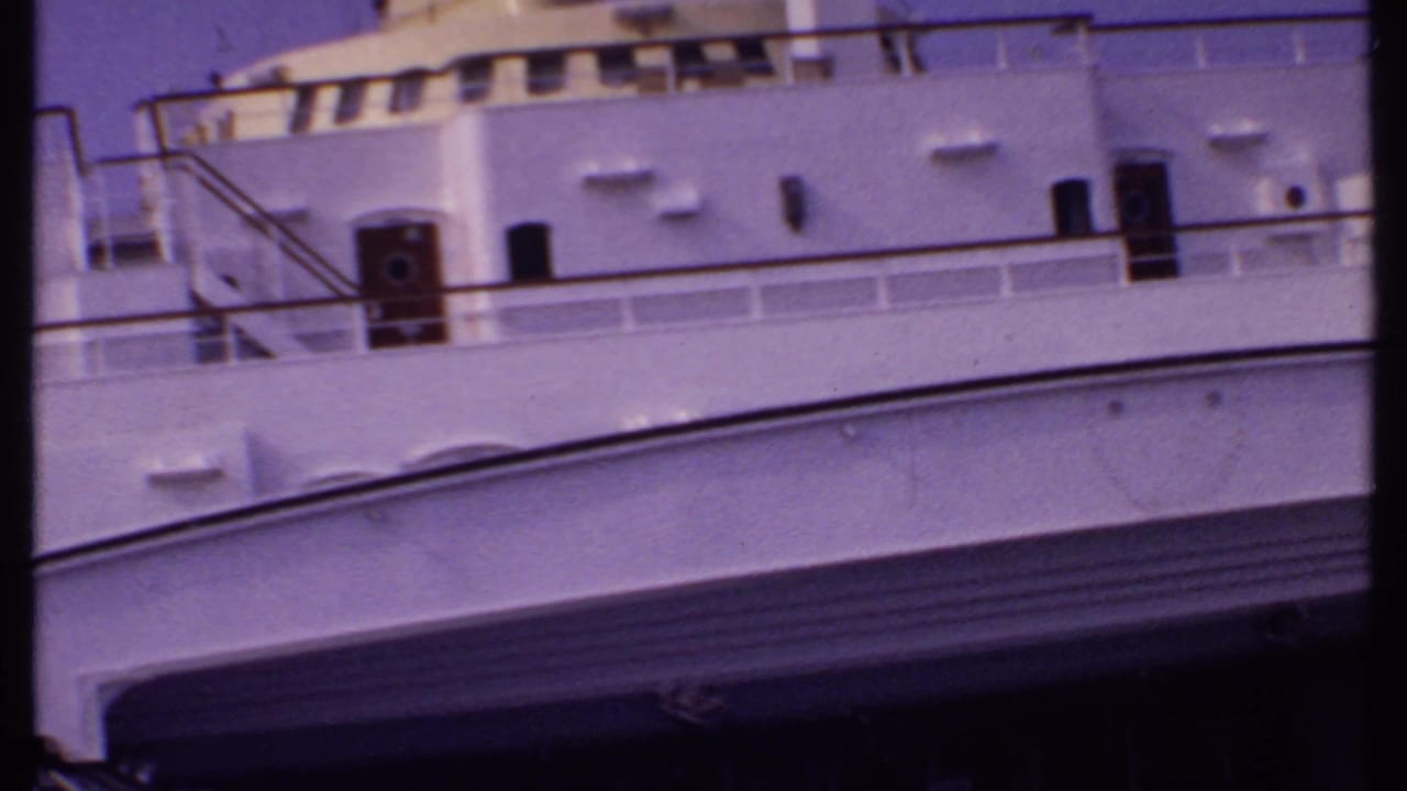 White cruise ship decks and railings seen through a handheld 8mm frame.