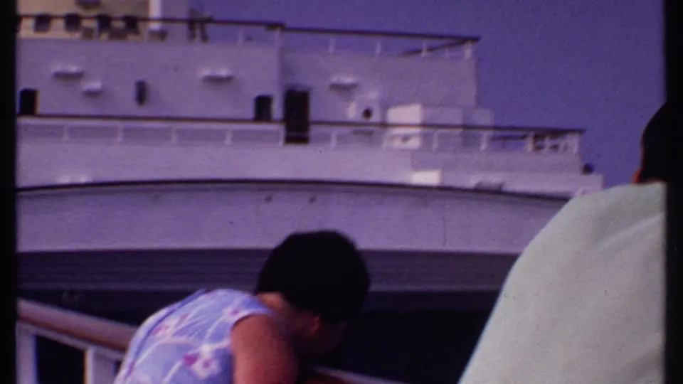 A woman in a floral dress leans at the rail on a Bahamas cruise ship in 1969, with white decks behind her.