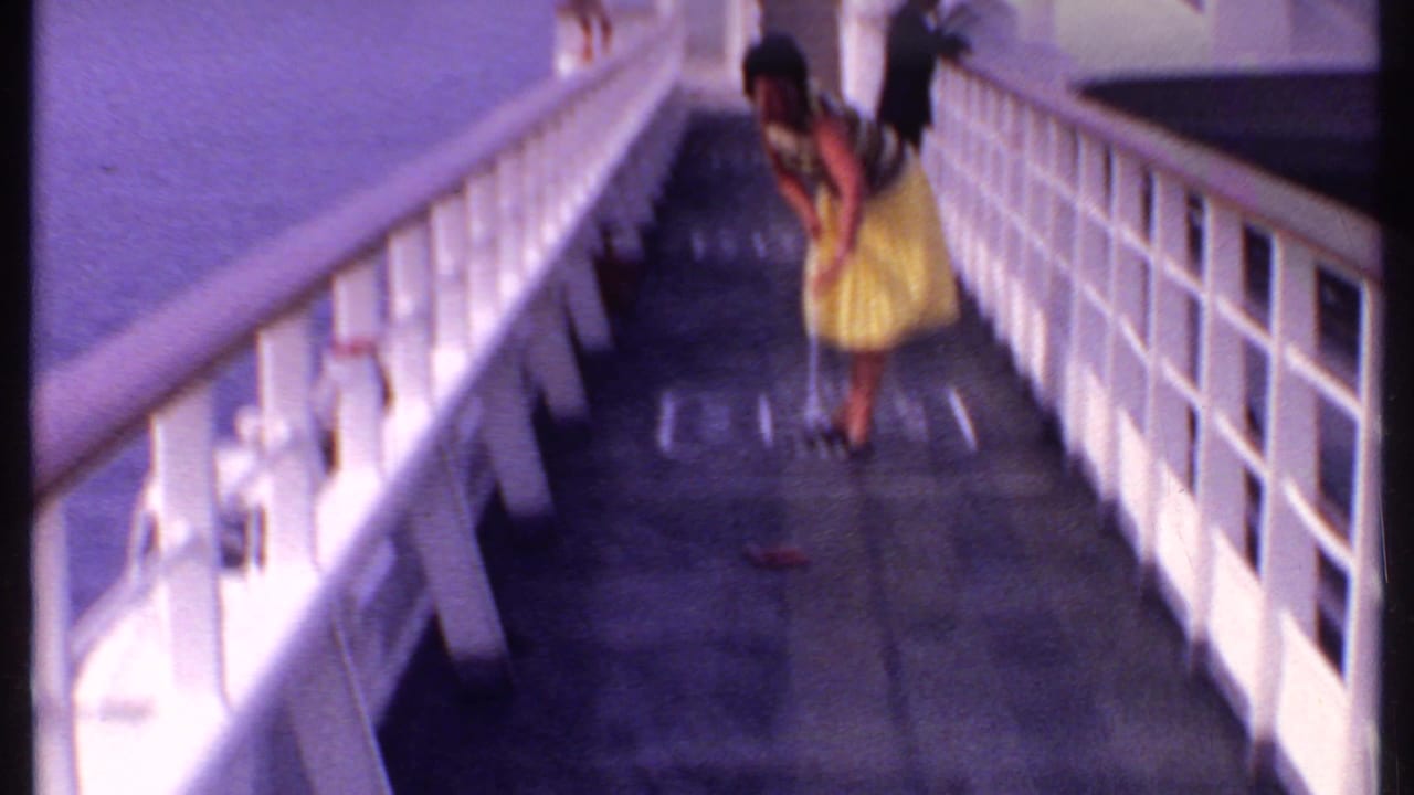 Woman in a yellow dress on a ship deck beside white railings.