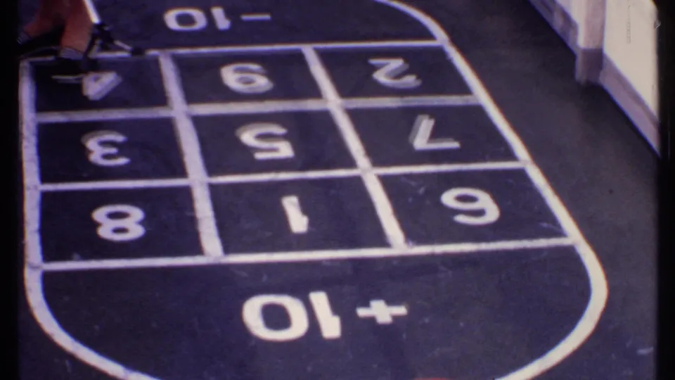 Close frame of a player's shoes beside the numbered shuffleboard court on the ship deck.