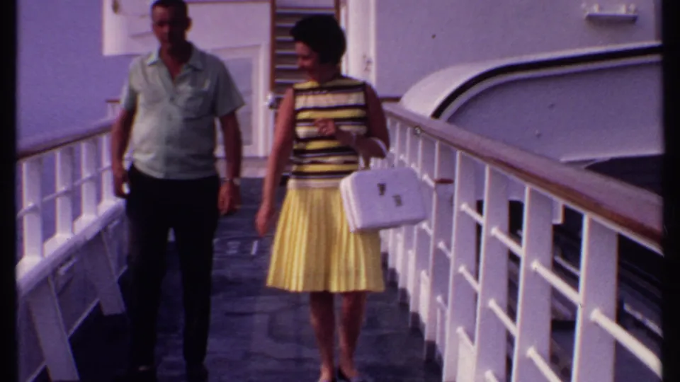 Near the end of the clip, the couple is closer to the camera on the ship deck, with white railings and vessel structure filling the frame.