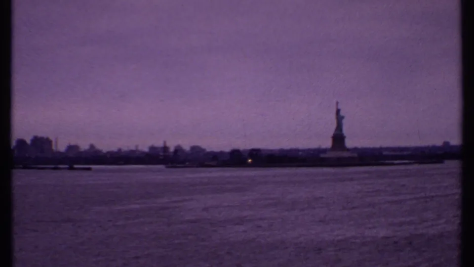 1969 8mm view across New York Harbor toward the Statue of Liberty and a low distant skyline.