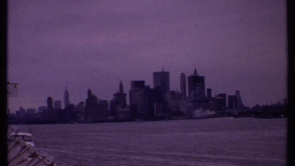 1969 8mm boat view toward the New York City skyline, with harbor water in the foreground and railing at the lower left.