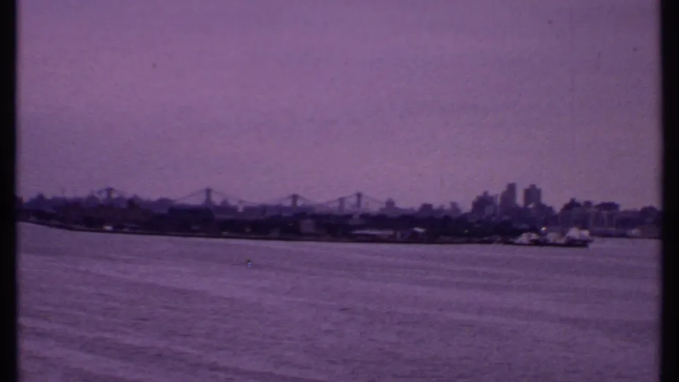 1969 Bahamas 8mm frame centered on a distant bridge and shoreline, with city buildings near the right edge.