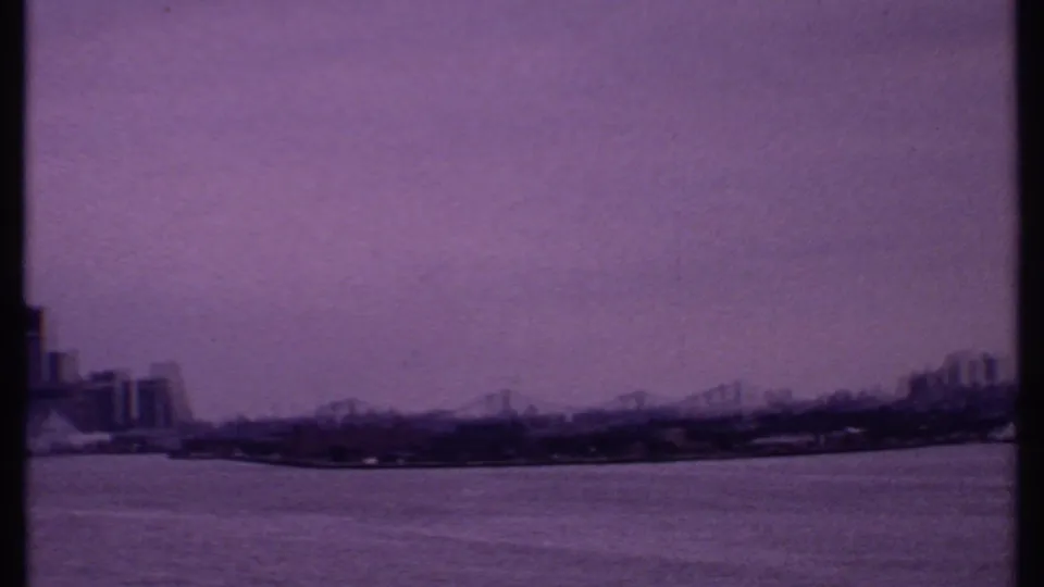 1969 Bahamas 8mm frame showing open water, a distant bridge, and partial skyline at the far edges of the pan.