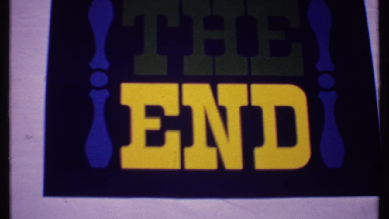 1969 Bahamas 8mm frame showing a THE END title card with yellow block letters, green upper text, blue decorative borders, and pale film edge.