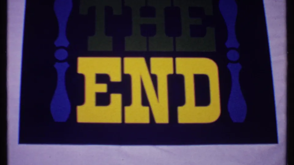 1969 Bahamas 8mm frame with a centered THE END title card, yellow lettering, faint green THE text, blue side ornaments, and visible frame edge.