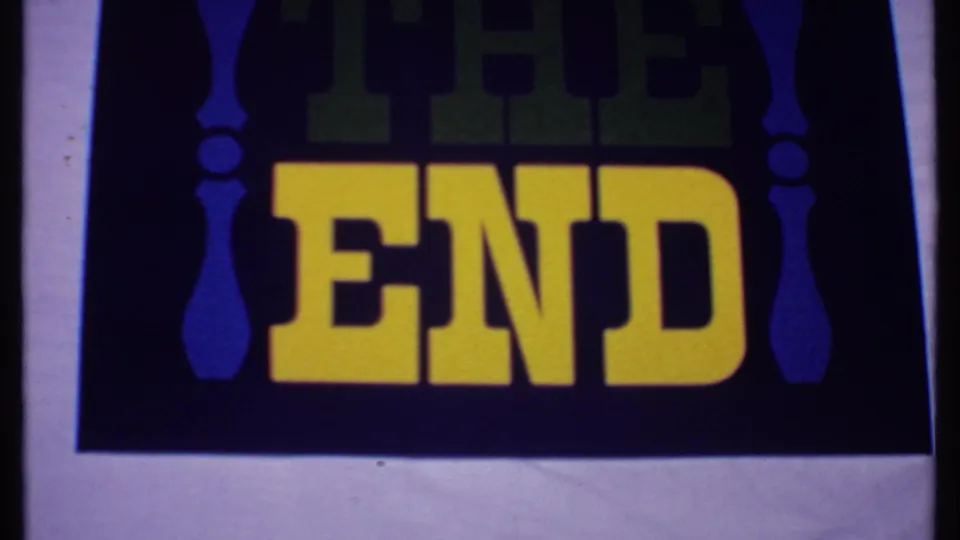 1969 Bahamas 8mm frame showing a cropped THE END card with yellow block letters, darker green upper text, blue side decoration, and visible grain.