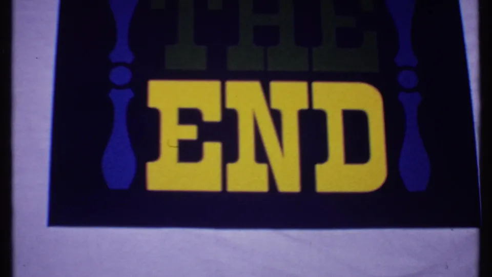 1969 Bahamas 8mm frame of the closing THE END card, showing yellow lettering, blue vertical ornaments, dark background, and film-edge variation.