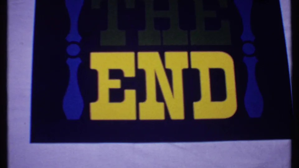 1969 Bahamas 8mm frame showing the end title cropped by the film edge, with yellow letters and blue ornament shapes.