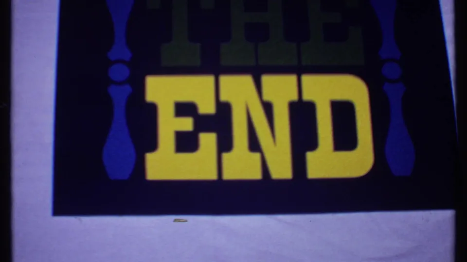 1969 Bahamas 8mm frame of the THE END card, with bold yellow lettering, dark field, and minor film speckling near the bottom.