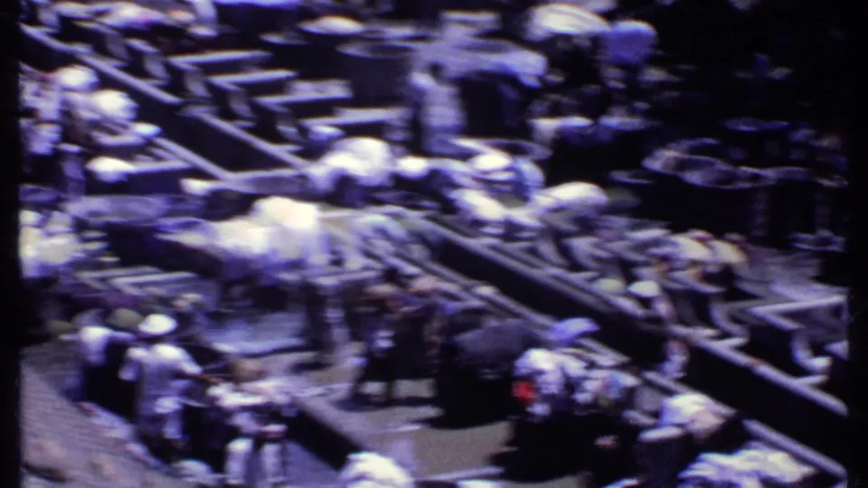 Motion-blurred 1969 India 8mm view of people washing or carrying laundry beside concrete troughs and basins.