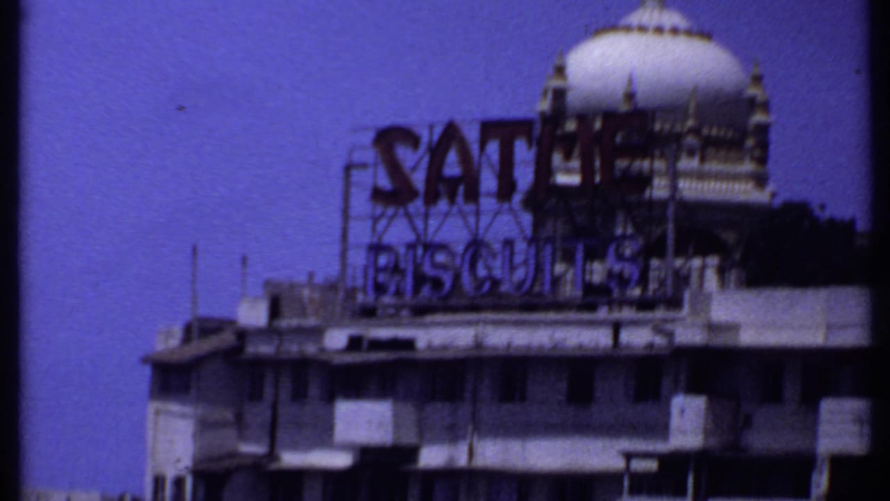 Close view of a waterfront building with a Sathe Biscuits rooftop sign and white dome.