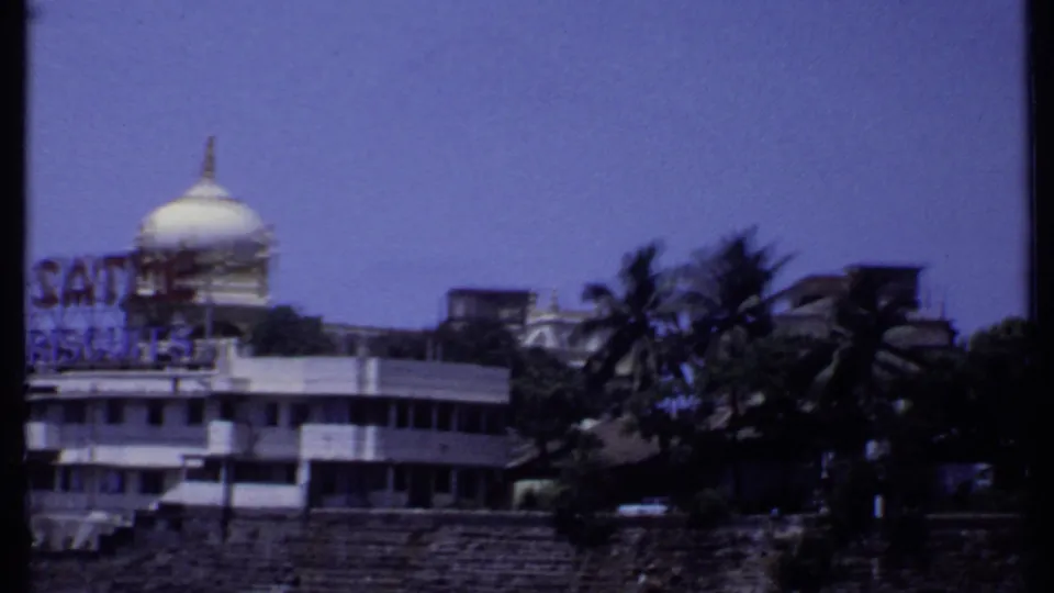 1969 India 8mm frame with a soft view of the Sathe Biscuits waterfront building, white dome and palms in the foreground.