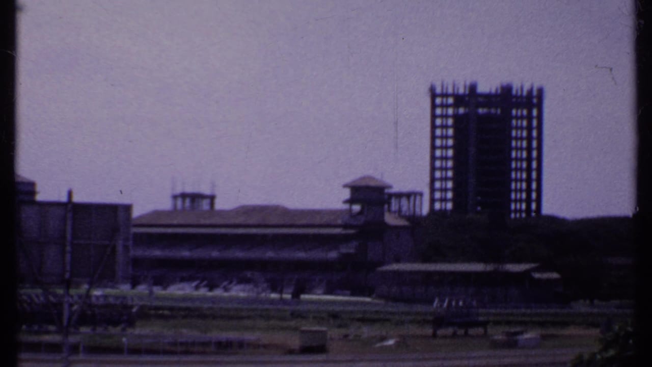 Distant stadium or racetrack grandstand with unfinished tall building behind it.