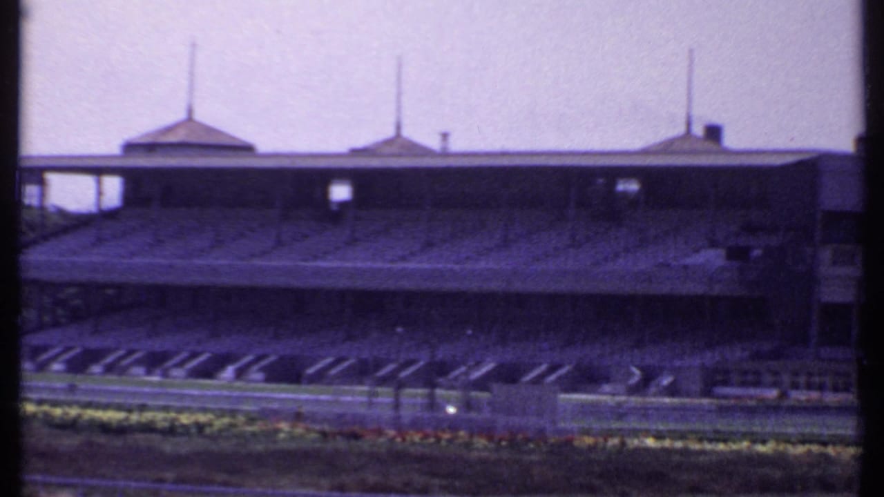 Empty racetrack with covered grandstand and domed roof structures in the background.