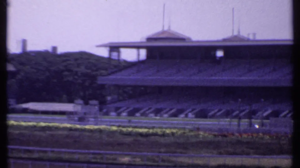 1969 India frame with an empty racetrack foreground and a large grandstand or clubhouse structure across the course.