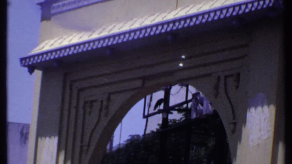 1969 India 8mm frame of a traditional-looking building entrance with a broad arch, decorative awning, and shadowed interior view.