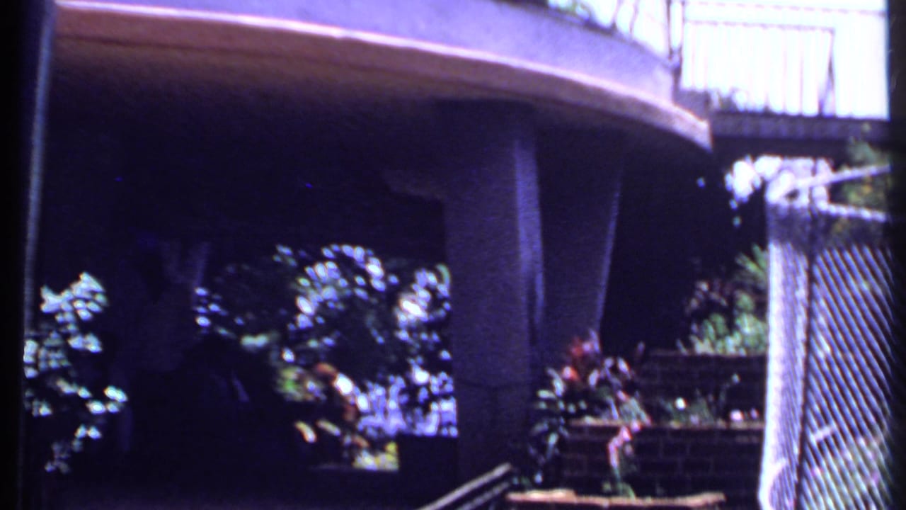 Concrete structure beside dense garden foliage and a curved railing.
