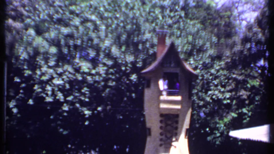 1969 India 8mm frame showing a narrow lookout tower framed by trees, with two people visible on its balcony.
