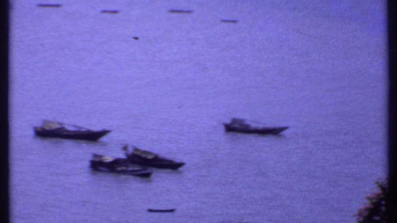 Small wooden boats floating on calm blue-purple water.