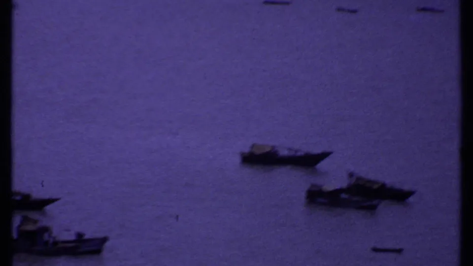 1969 India home-movie view of small boats on open coastal water, framed by dark shoreline edges.