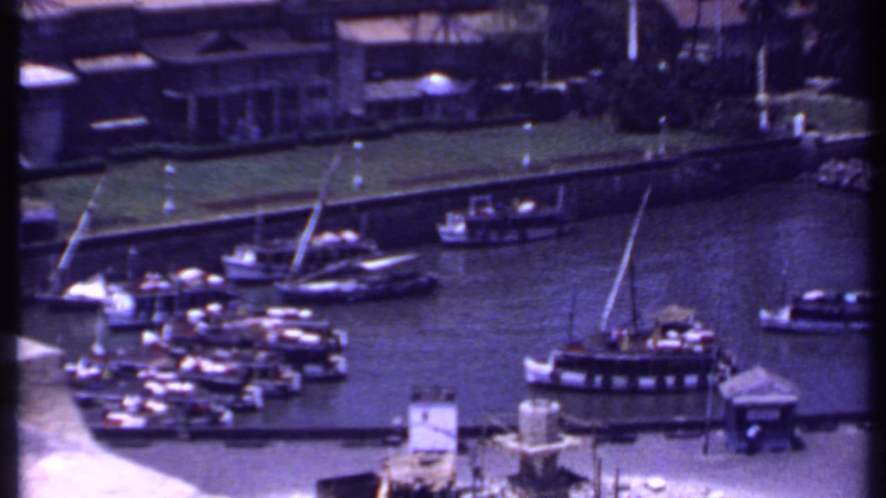 Small boats docked in a harbor beside low waterfront buildings.