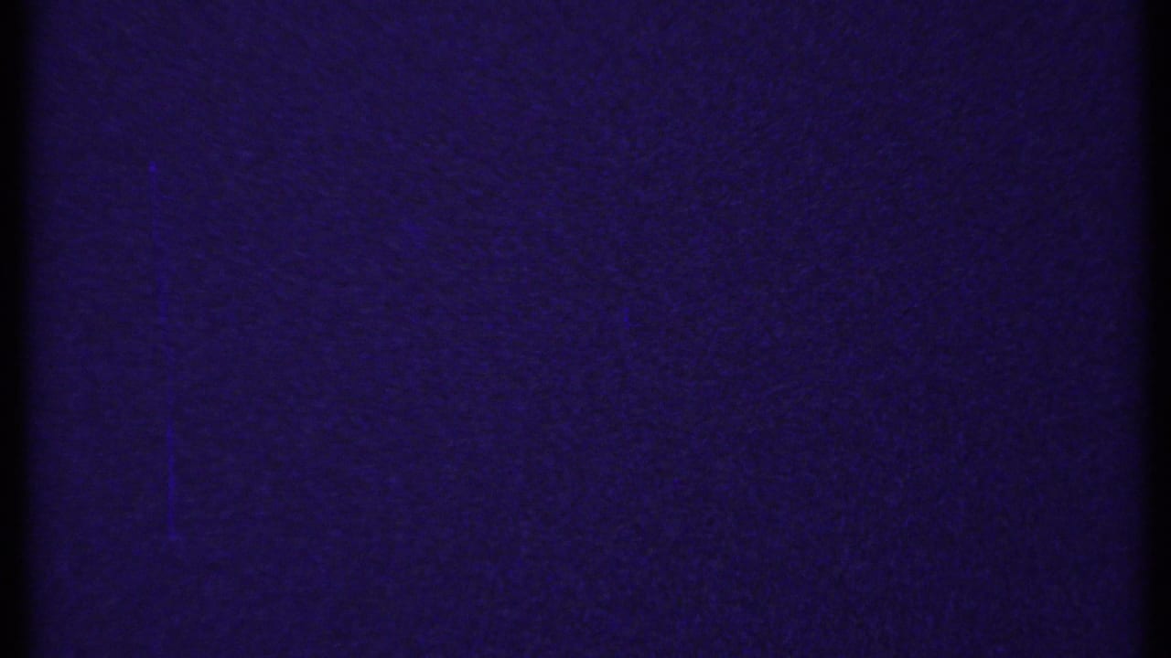 Dark, grainy purple 8mm frame, likely leader or an underexposed transition with no clear subject visible.
