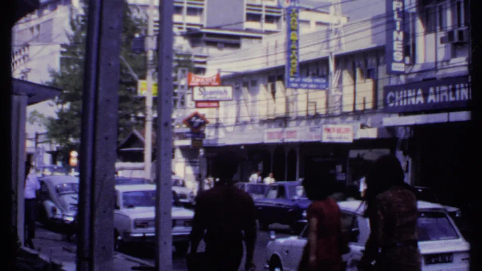1969 India commercial street with pedestrians, older cars, a Beetle, storefront signs, and a visible China Airlines sign.