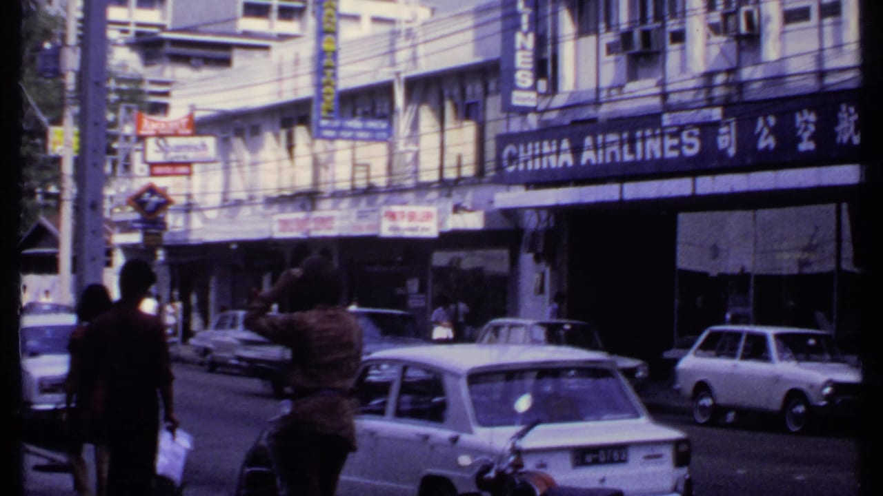 Street traffic and pedestrians pass beneath a China Airlines sign and Chinese characters on a building facade.
