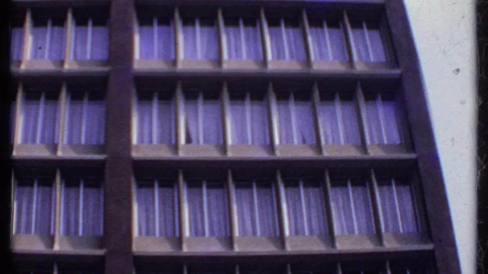 1969 India 8mm frame showing stacked rows of windows and drapes beside a pale wall edge during an upward pan.