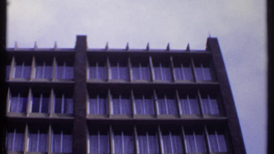 1969 India 8mm frame showing the motel facade from below, with repeated window rows and a strong vertical concrete structure.