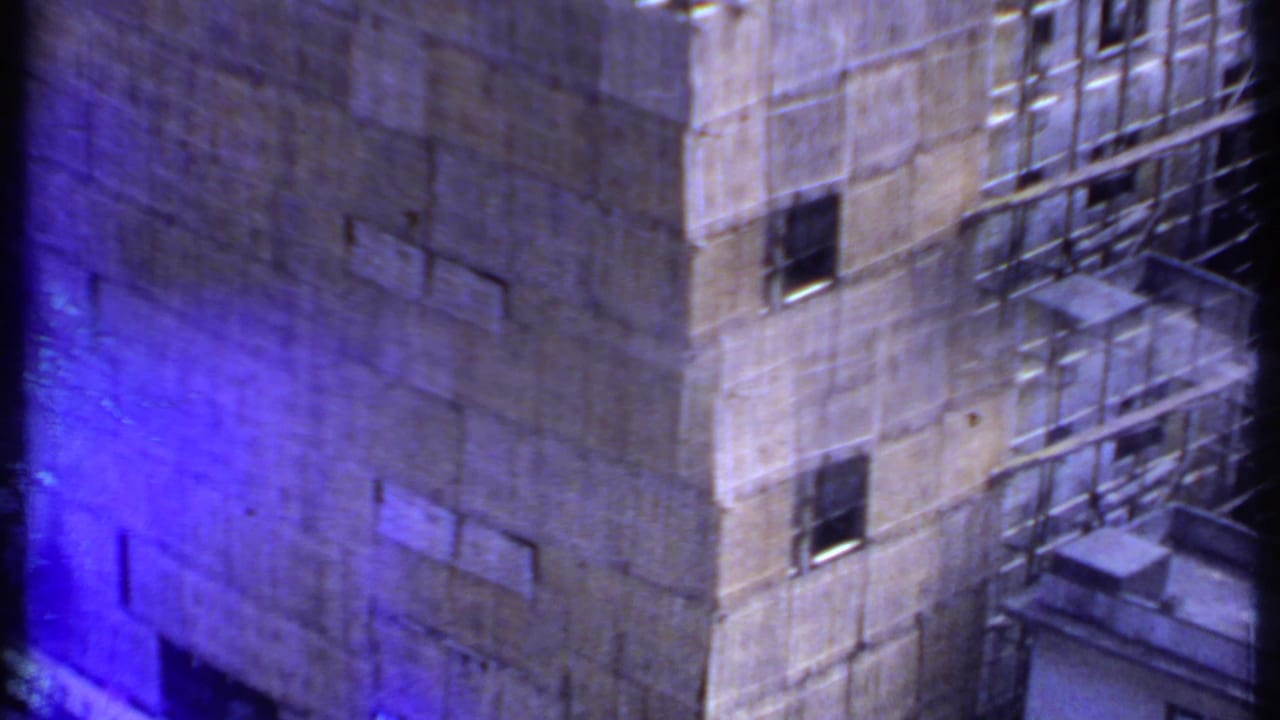 1969 India 8mm frame of a scaffolded concrete building facade, with window openings and a blue color flare from the film image.