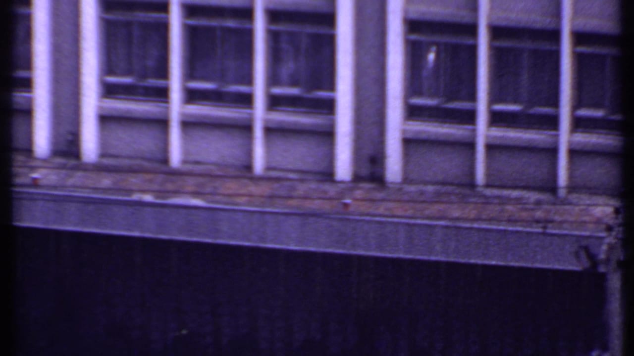 Building facade with windows, columns, and a dark vertical obstruction near the center.
