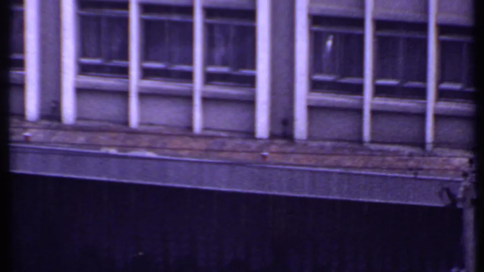 1969 India 8mm frame of the office building facade, partly crossed by a dark vertical foreground shape during the pan.