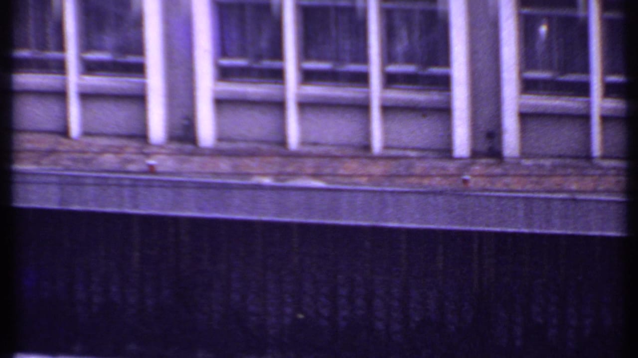 1969 India 8mm frame showing a closer view of the office facade, with repeated windows, white fins, and a dark wall below.