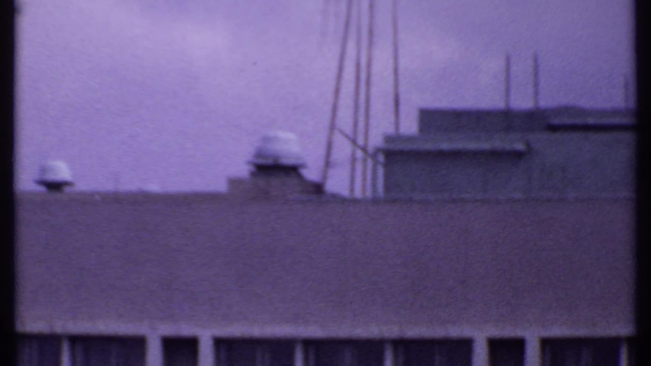 1969 India 8mm frame showing rooftop utility details, vents, poles, and a low parapet under a purple color cast.