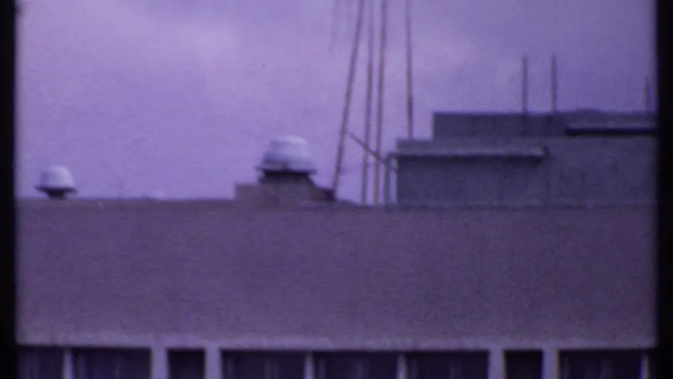 1969 India 8mm frame showing rooftop utility details, vents, poles, and a low parapet under a purple color cast.
