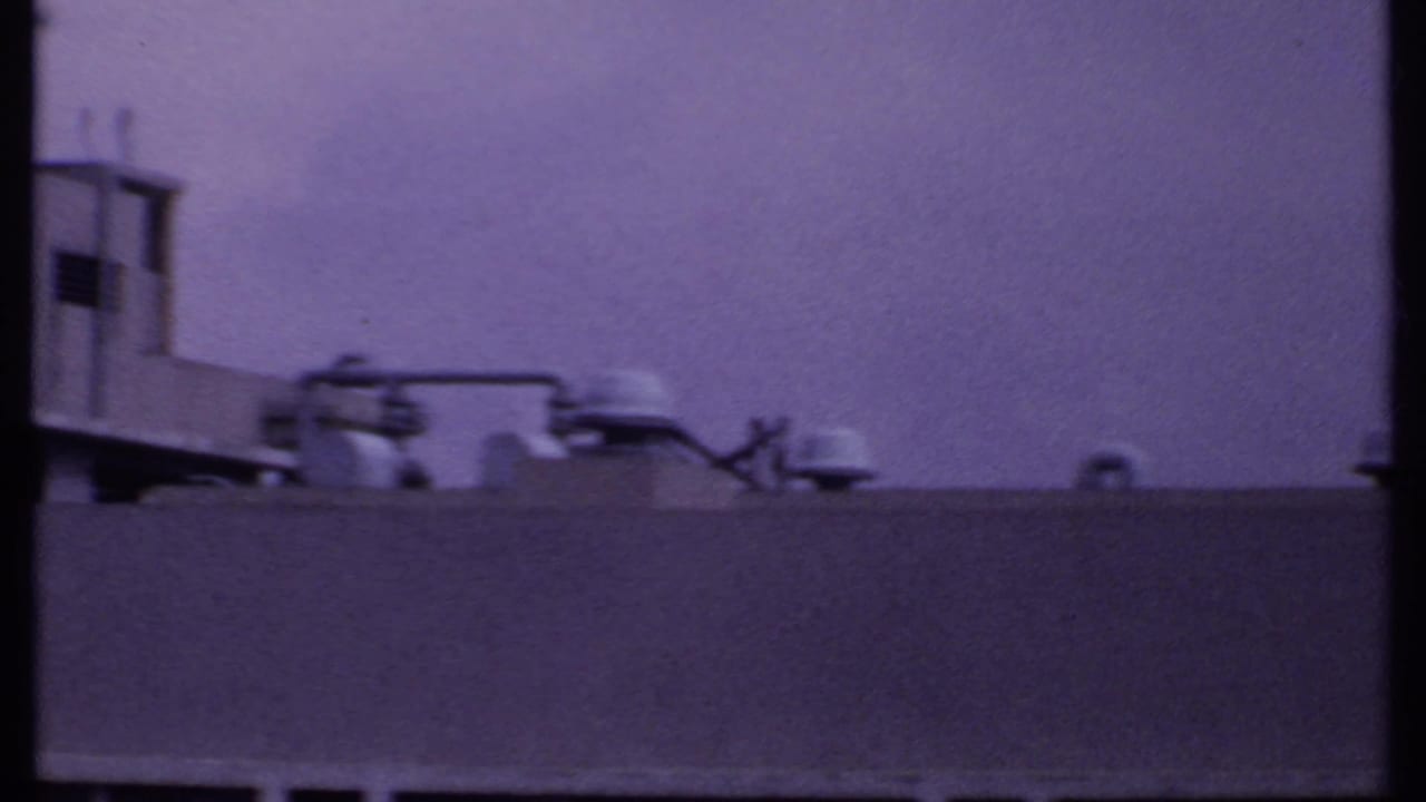 1969 India 8mm frame of rooftop mechanical details and pipes behind a plain parapet, with no readable markings.