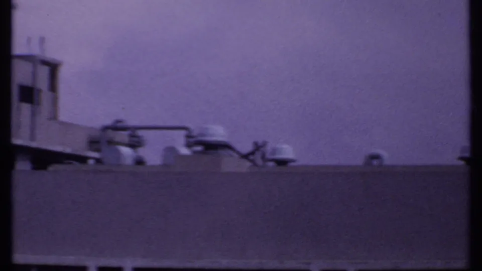 1969 India 8mm frame of rooftop mechanical details and pipes behind a plain parapet, with no readable markings.