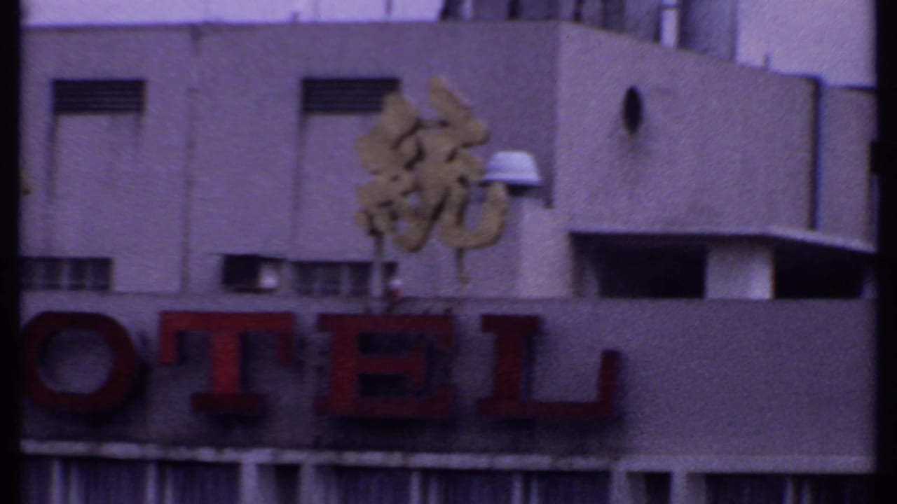 Red HOTEL sign on a concrete building with gold Chinese characters above and rooftop vents nearby.