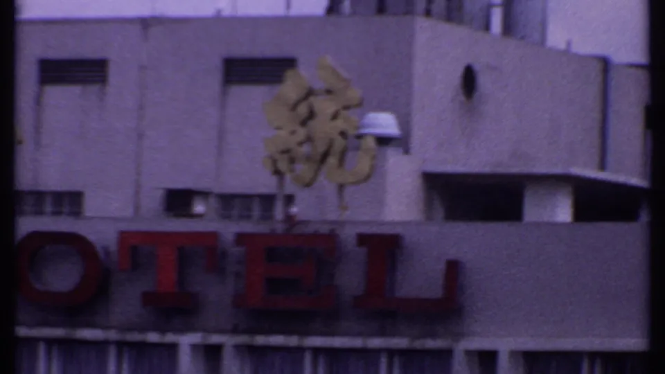 1969 India 8mm frame showing red HOTEL letters below gold Chinese characters on a weathered commercial building facade.