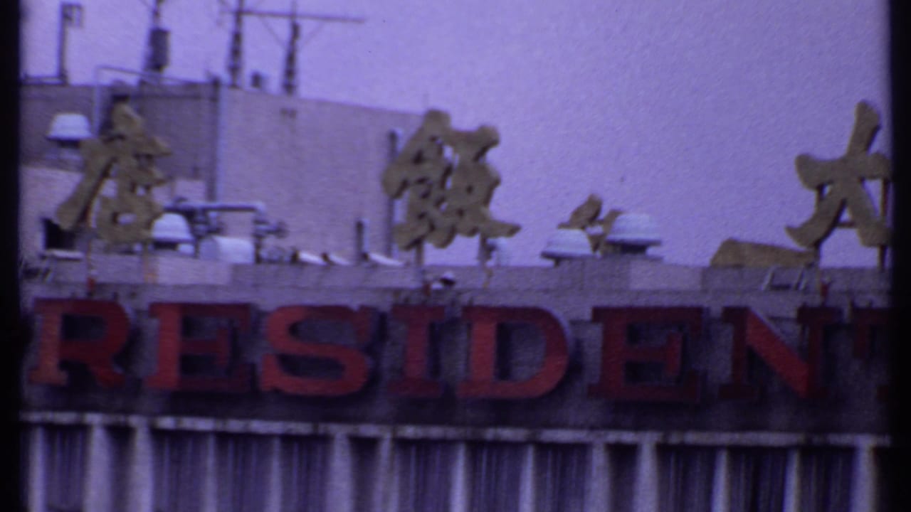 Close view of a hotel facade with red RESIDENT lettering and Chinese characters above.