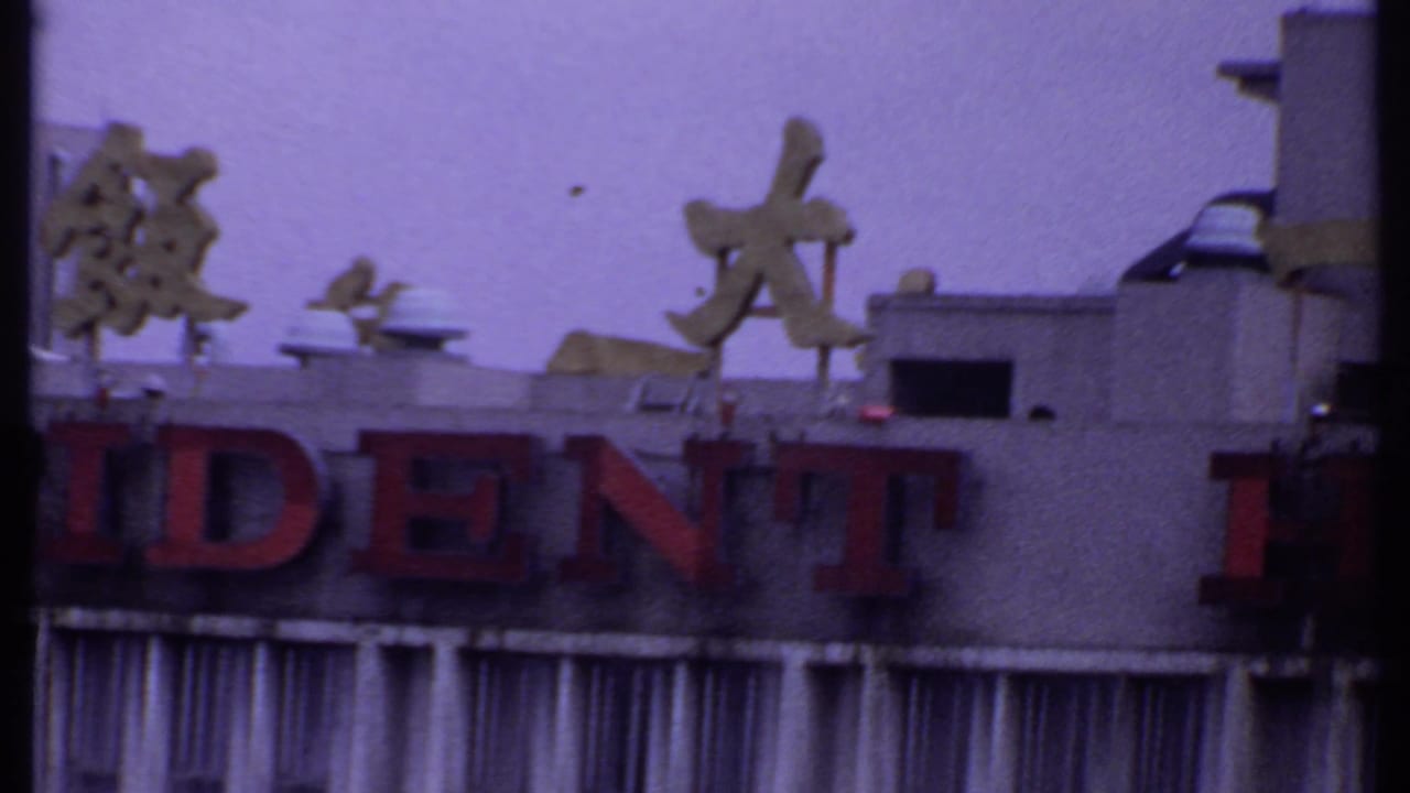 1969 India travel frame focused on the Resident Hotel facade, showing partial red lettering, Chinese characters, and rooftop equipment.