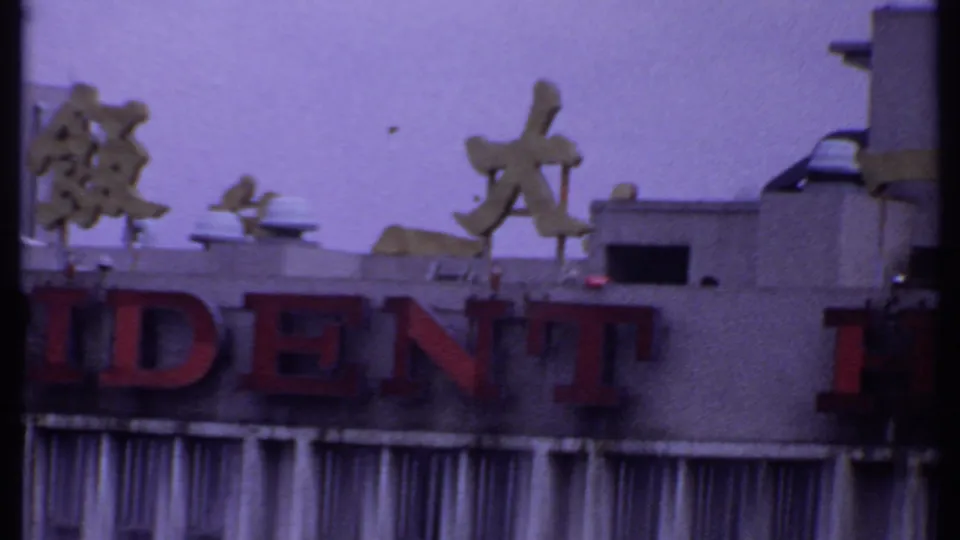 1969 India travel frame focused on the Resident Hotel facade, showing partial red lettering, Chinese characters, and rooftop equipment.