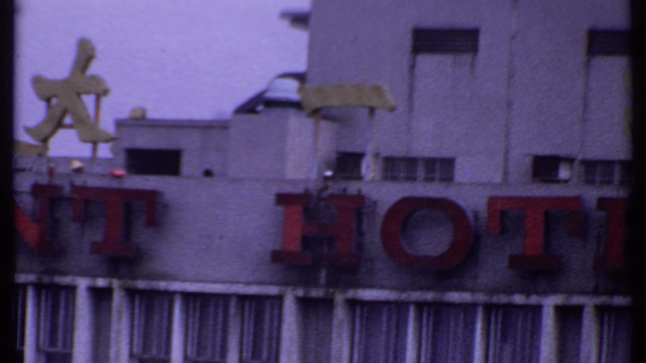 1969 India 8mm frame showing part of the Resident Hotel sign, including red HOTEL letters, Chinese characters, and narrow vertical windows.