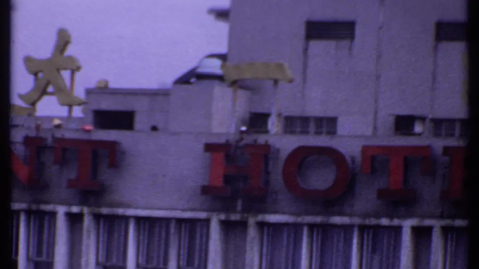 1969 India 8mm frame showing part of the Resident Hotel sign, including red HOTEL letters, Chinese characters, and narrow vertical windows.