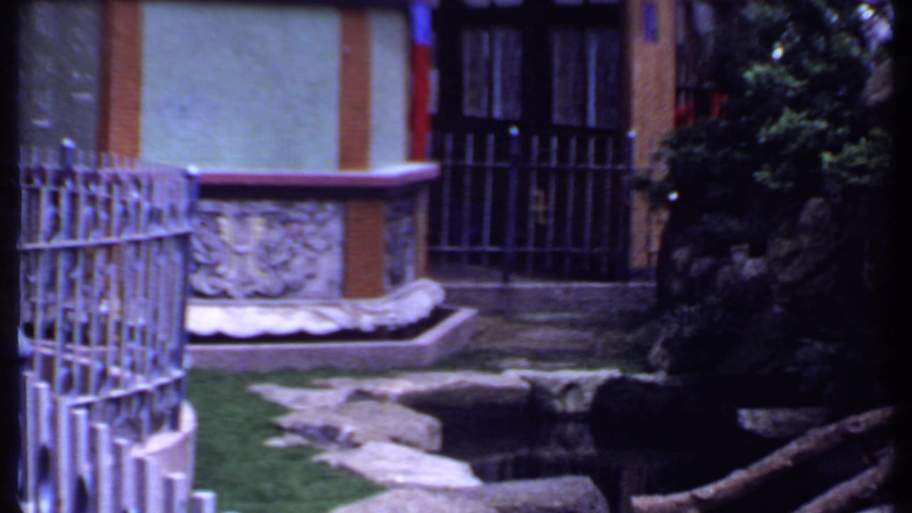 Curved metal fence beside a carved stone fountain and barred doorway.