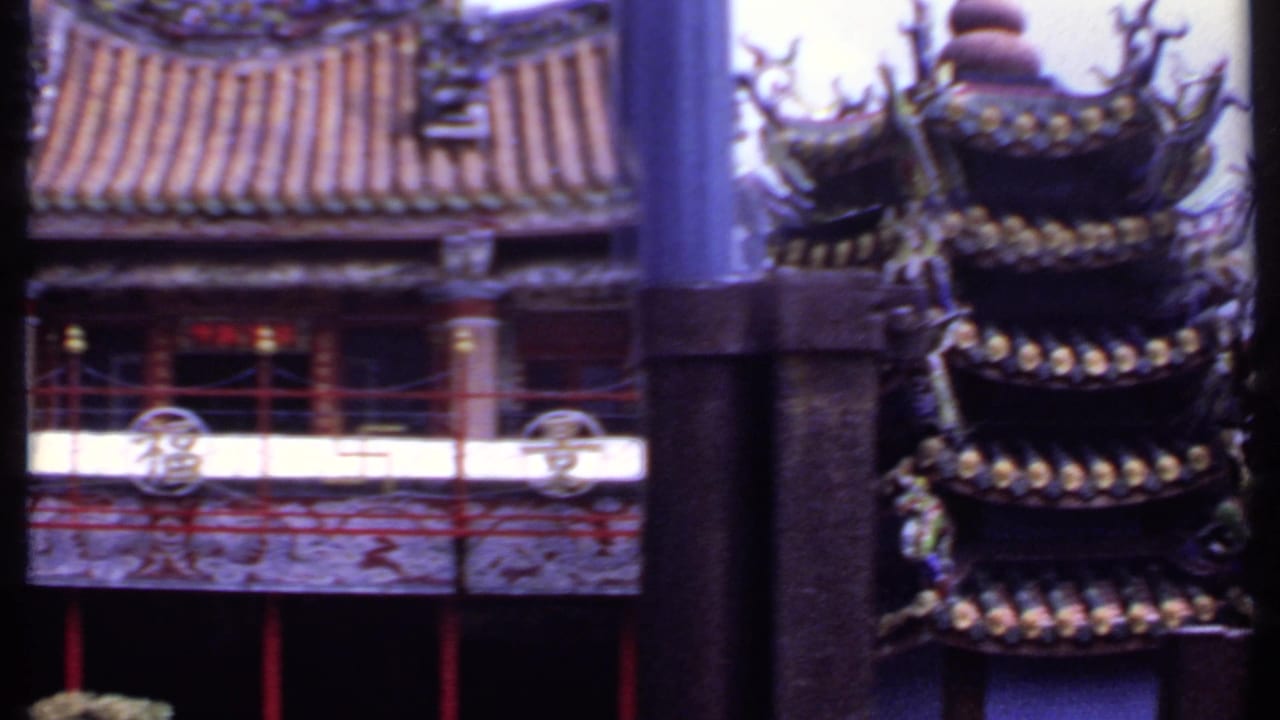Chinese-style temple facade with tiled roof, red railings, and circular balcony ornaments.